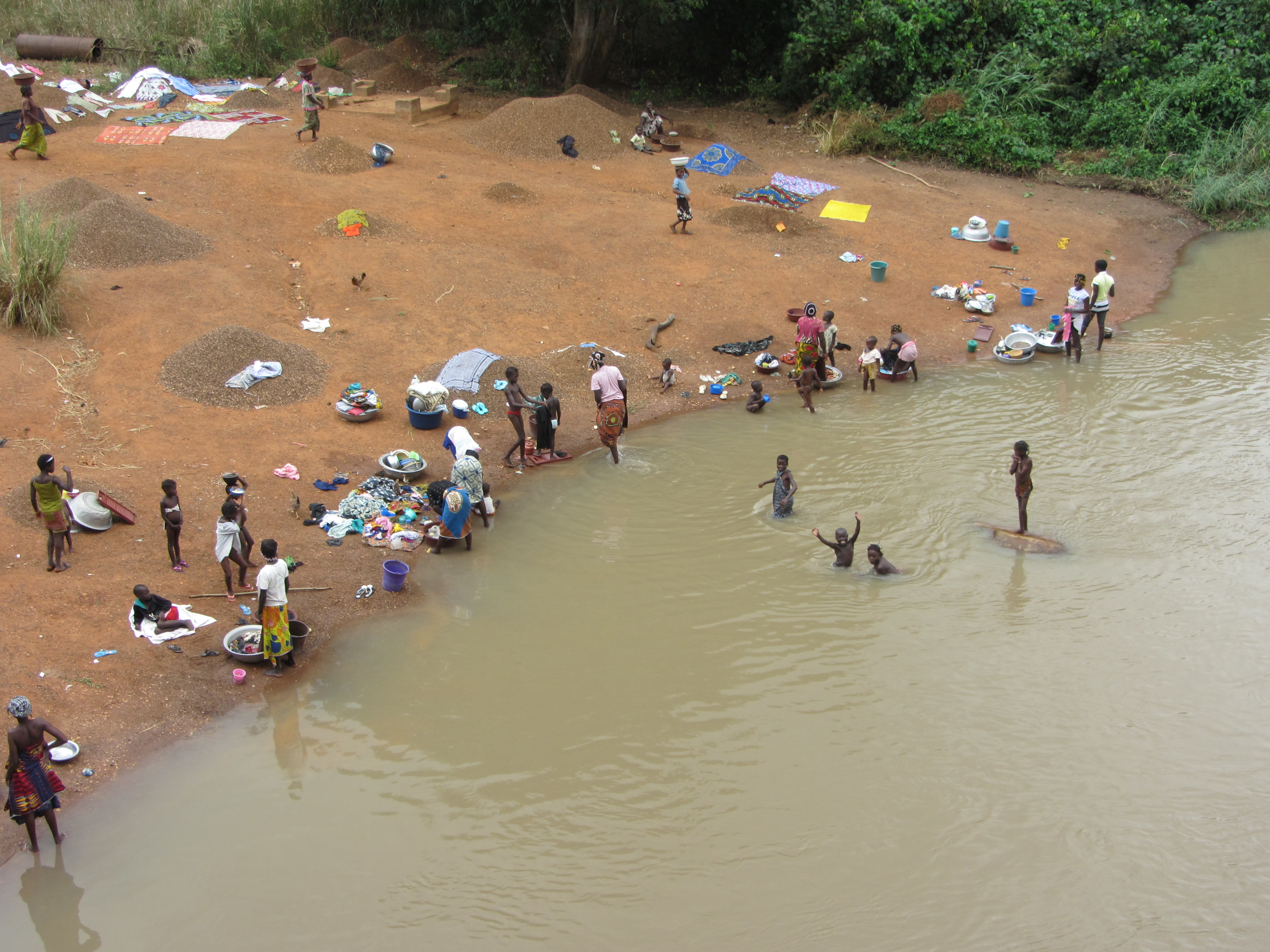 Mujeres y niños lavando y bañándose a la vera del río